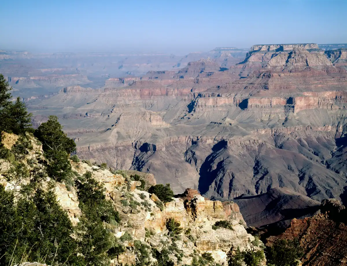 Layered red and tan cliffs of the Grand Canyon stretching into the haze from a rim viewpoint