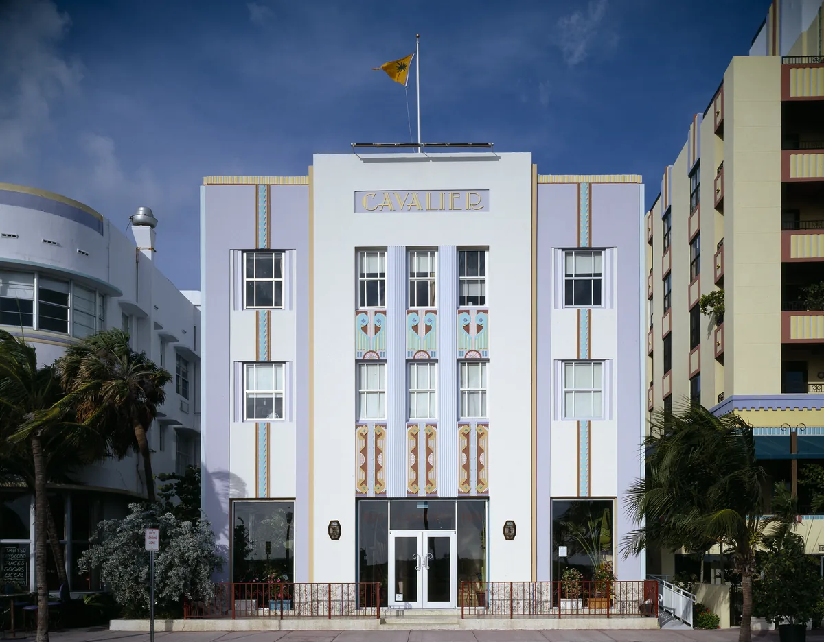 Cavalier Hotel, an Art Deco building in Miami Beach, with a flag on its roof and palm trees in front